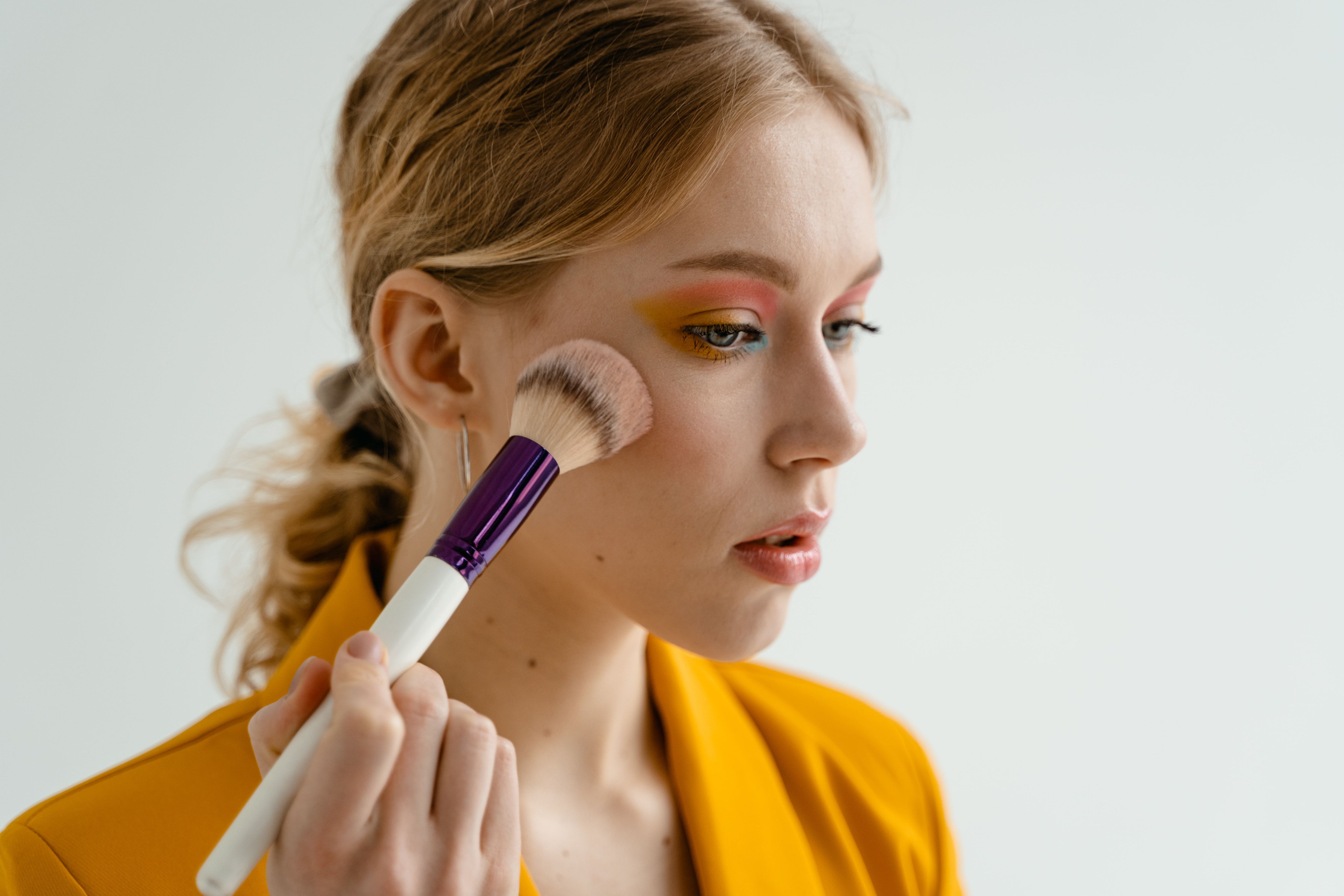 Woman applying warm bronzer and blush for a toasty makeup look