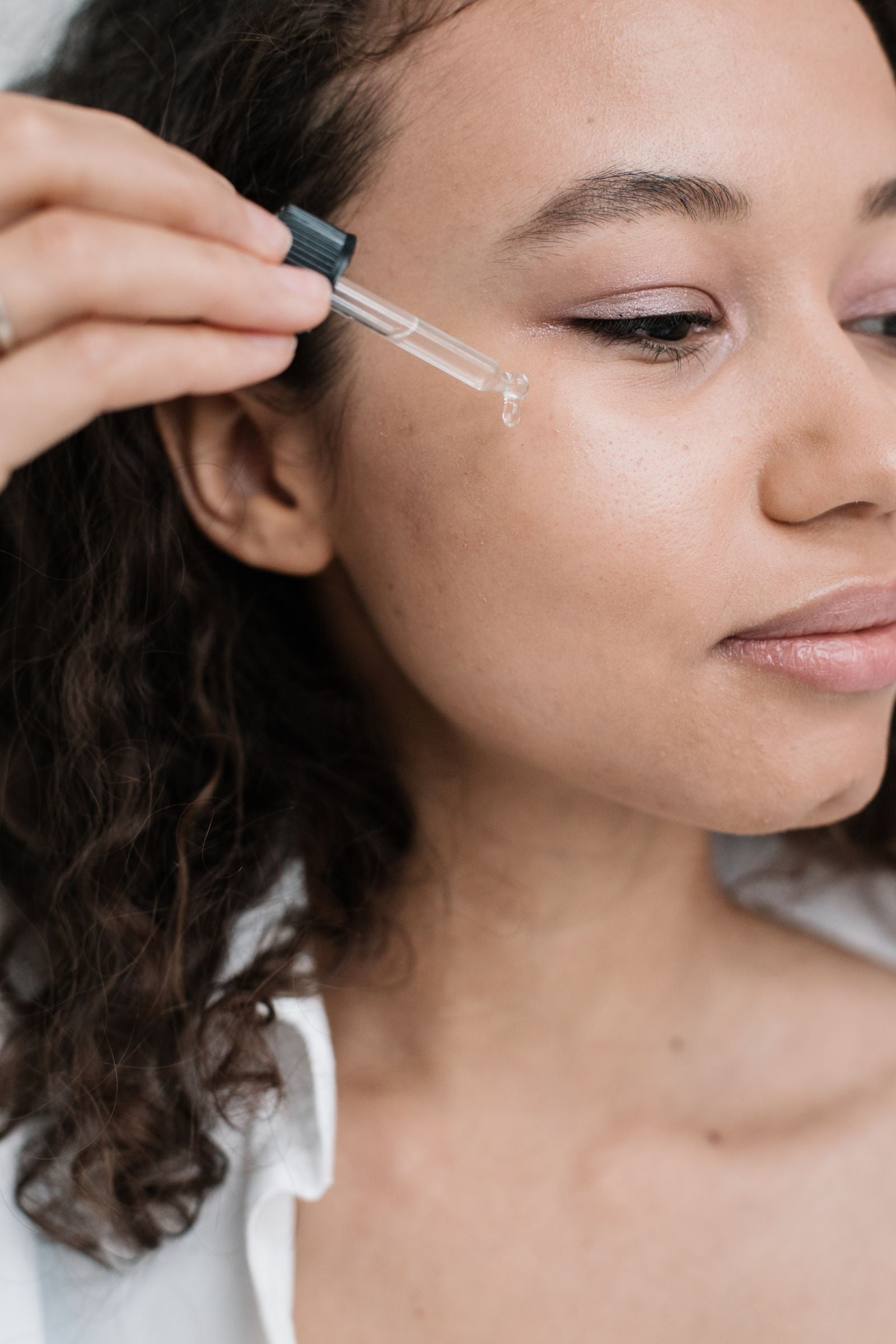 Young adult woman applying facial serum for a luminous glass skin or dewy skin look